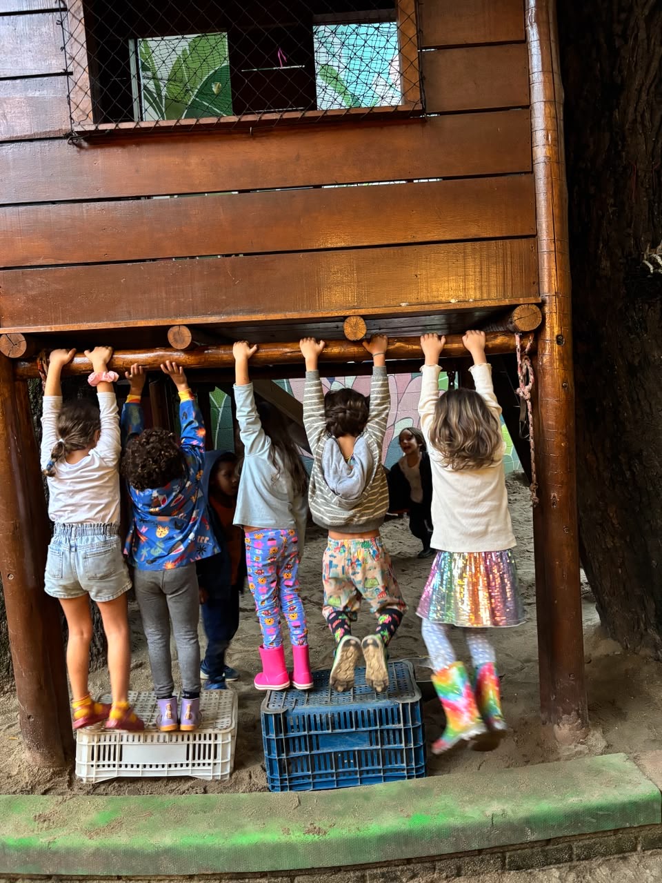 Crianças penduradas em uma estrutura de madeira no pátio da escola